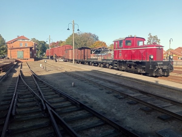 008<br />Um die auf der Ladestraße liegenden Schienen (links am Bildrand) verladen zu können, stellen wir die aufgeschemelten G-Wagen (DEV Gw 6 und Wg der Press)  nach Gleis 1a. Dort sehen wir einen für eine Schmalspurbahn schon recht beachtlichen Zug!